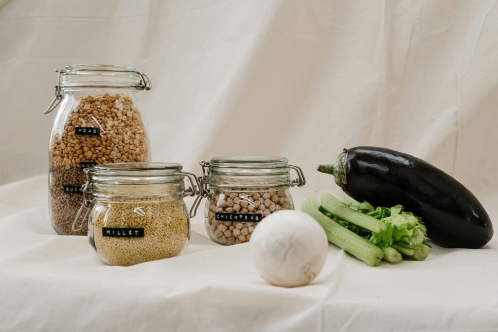 Glass jars of whole grains and millets, essential for a healthy Ayurvedic winter diet, placed next to fresh seasonal vegetables.