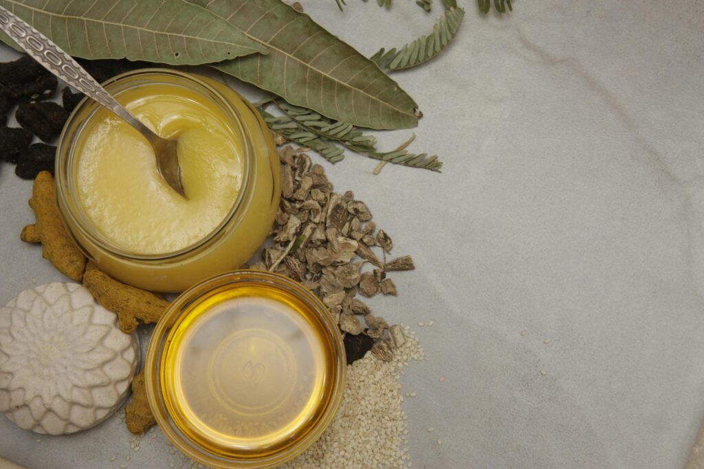 A jar of golden Ayurvedic ghee, a key winter food for strength, surrounded by other immunity-boosting ingredients like turmeric root and sesame seeds.